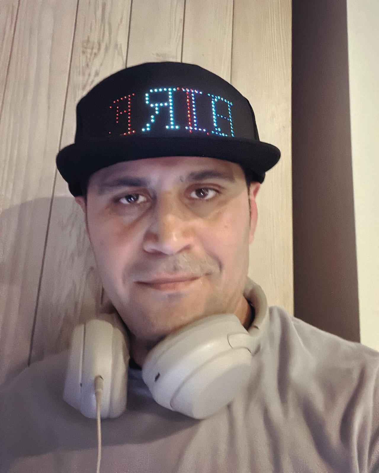 DJ Alphire wearing his signature LED cap with headphones around his neck