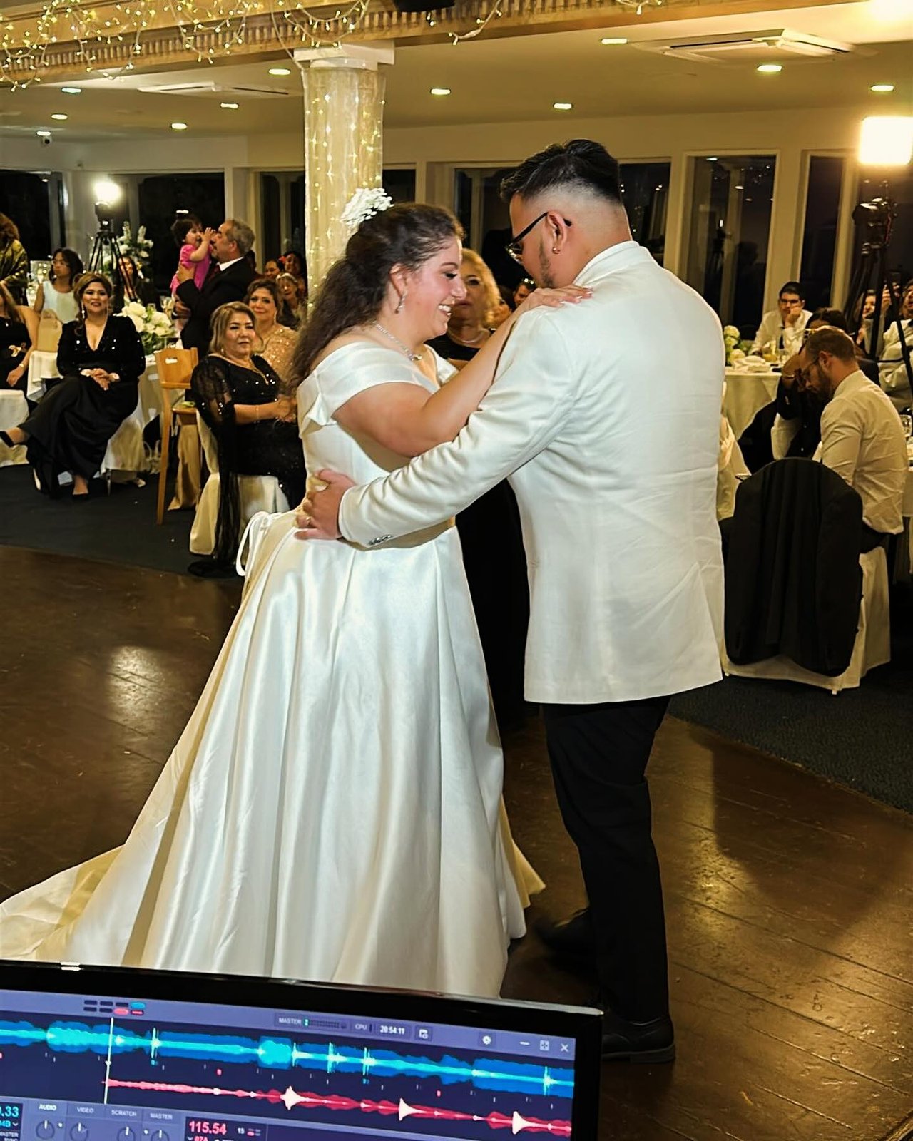 Newlyweds share their first dance with DJ Alphire's mixing setup in the foreground