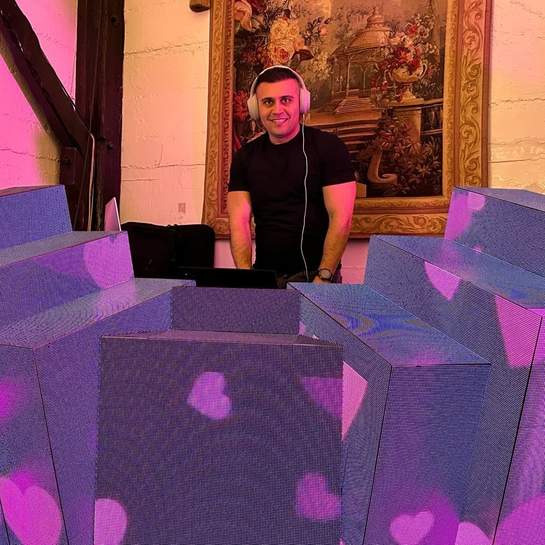DJ Alphire behind the decks surrounded by colorful LED panels